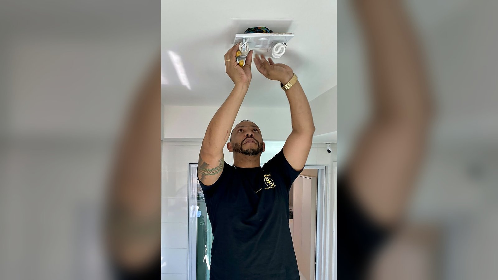 Colaborador da Bom Service ajustando uma luminária no teto